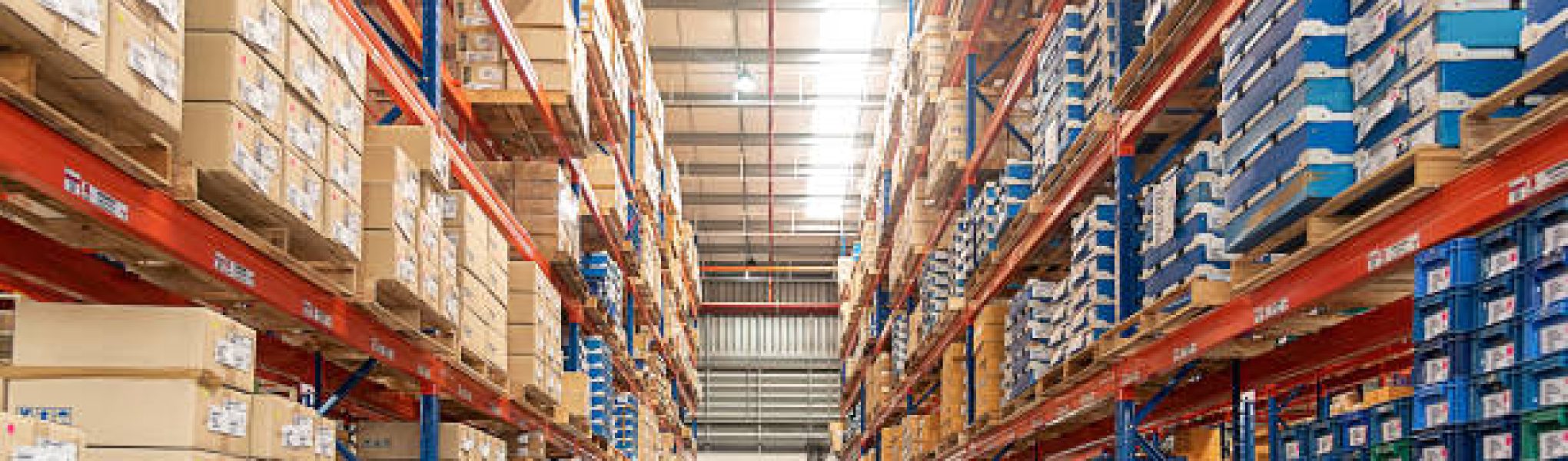 Rows of shelves with goods boxes in huge distribution warehouse at industrial storage factory.